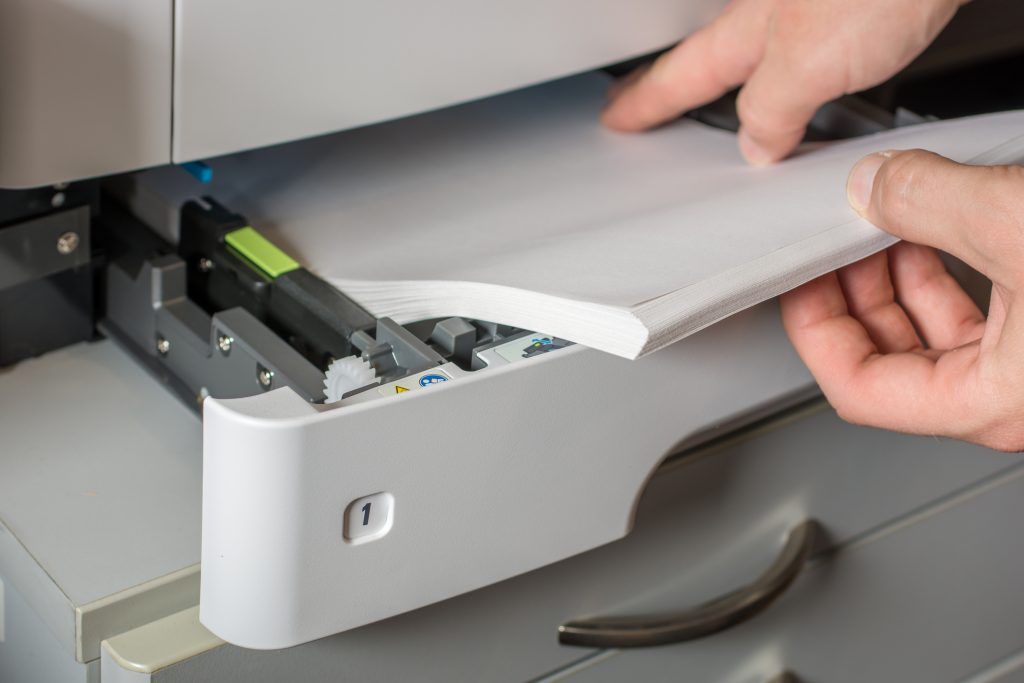 Checking the paper tray to see if there is paper in the office printer.