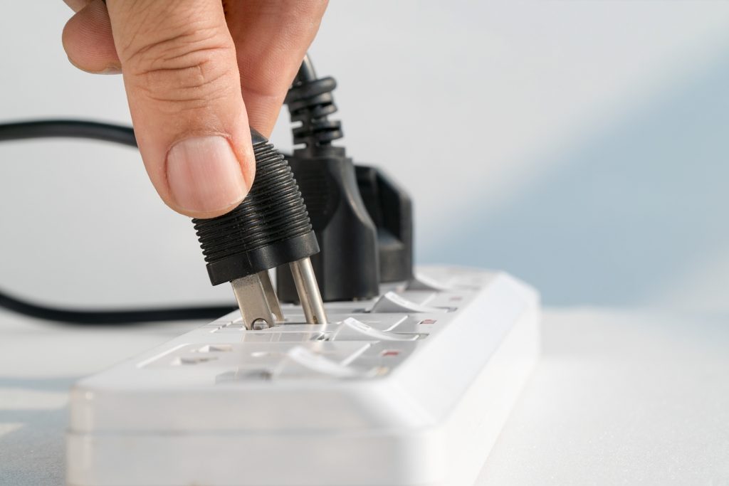Close up of hand plugging printer cord into a power bar.